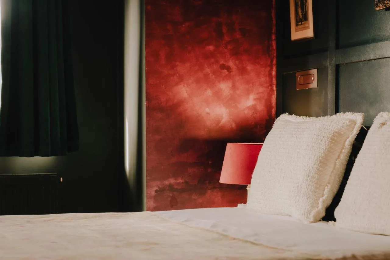A bedroom with a white bed with a red wall at The Galaxie in Oxford
